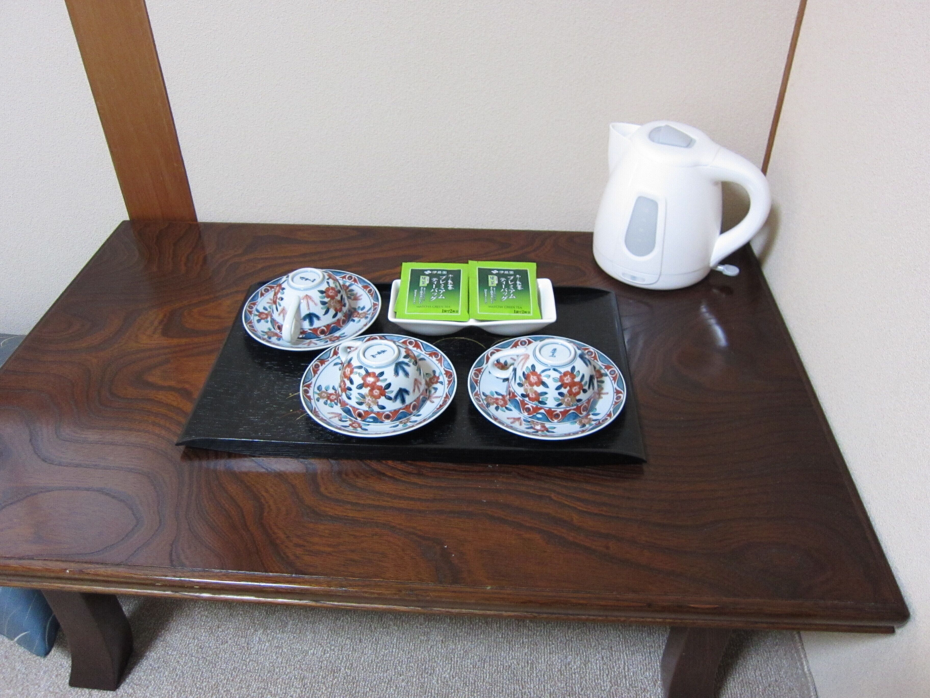 A small wooden table with four teacups, a teapot, and a tea box.