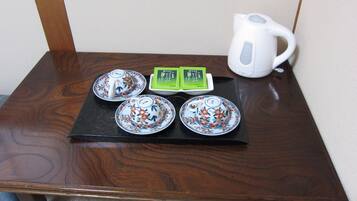 A small wooden table with four teacups, a teapot, and a tea box.