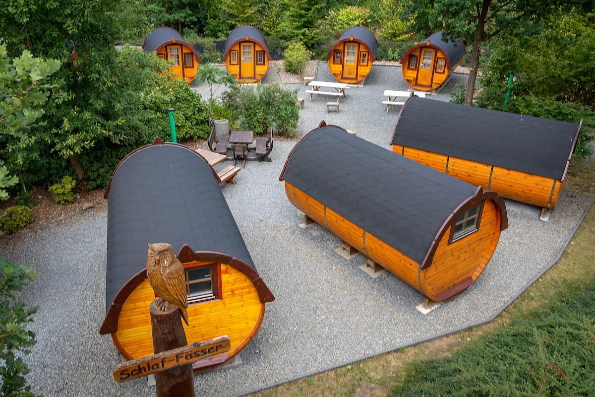 A series of wooden cabins with sloped roofs, arranged in a cluster with picnic tables and benches.