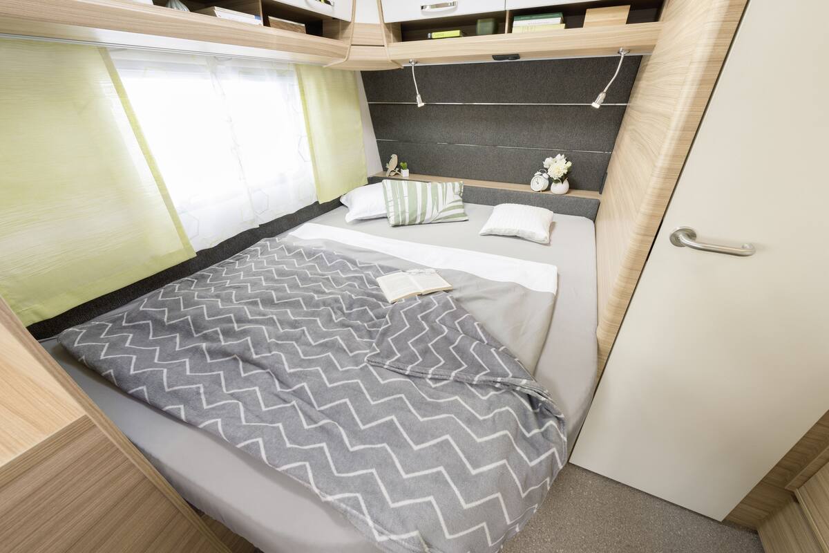 A compact bedroom with a bed, bedside table, and a small shelf with decorative items.