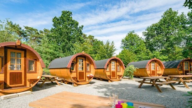 A row of wooden cabins with picnic tables in front. - Ferienpark Auf dem Simpel (Soltau)