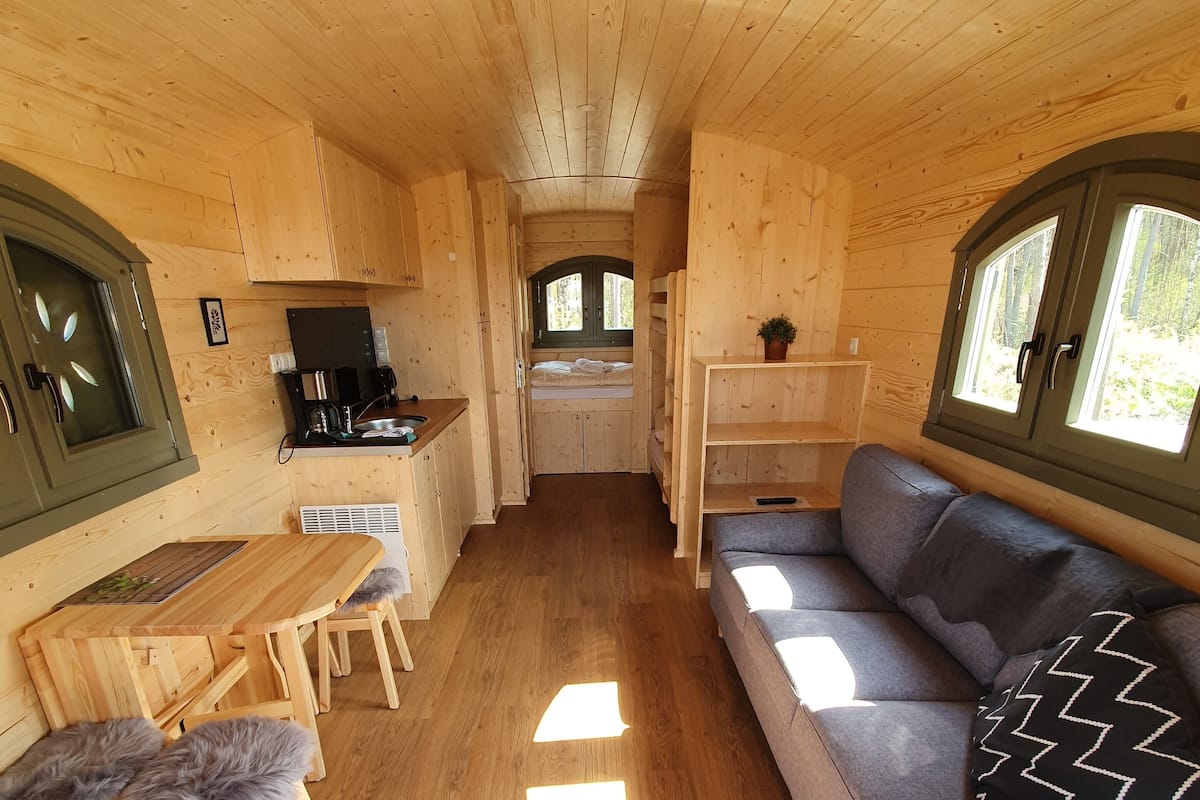 A compact, wooden interior with a kitchenette, a sofa, and a dining area.
