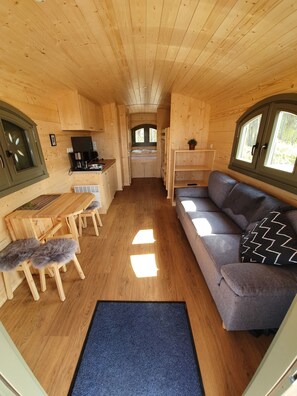 Un intérieur compact en bois comprenant un coin cuisine, un canapé et un espace repas.