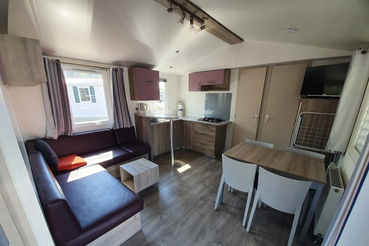 A compact living space with a sofa, a small table, a kitchenette, and a dining area.