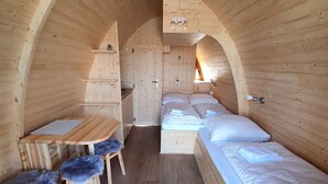 A cozy wooden cabin with a dining area, two beds, and a small kitchenette. - Ferienpark Auf dem Simpel (Soltau)