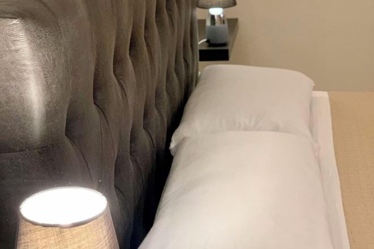 A bed with white bedding and a lamp on a bedside table.