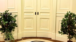 A double door with a circular floor design, flanked by potted plants. - Simon's Guest House Rome (Rome)