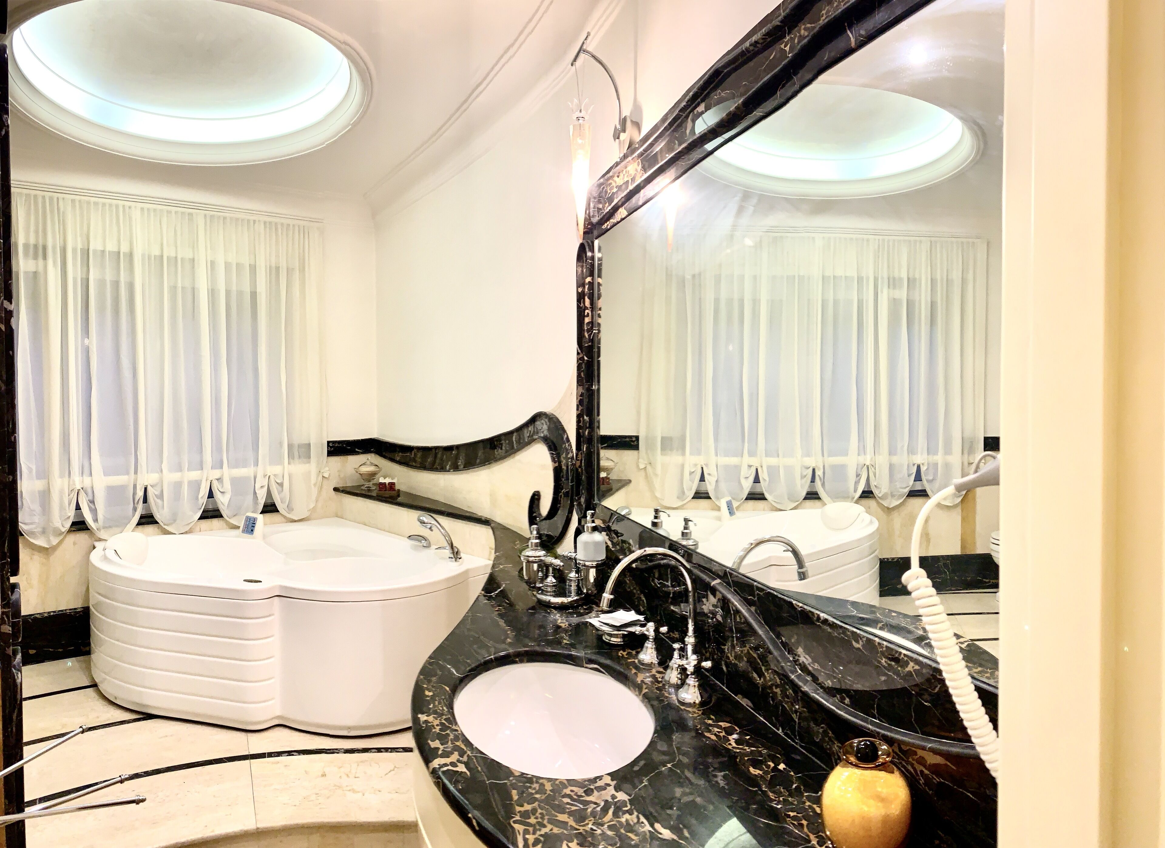A luxurious bathroom with a large mirror, a bathtub, a vanity with a sink, and a toilet.