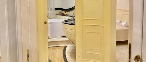 A hallway leading to a bathroom with a bathtub, a sink, and a toilet.
