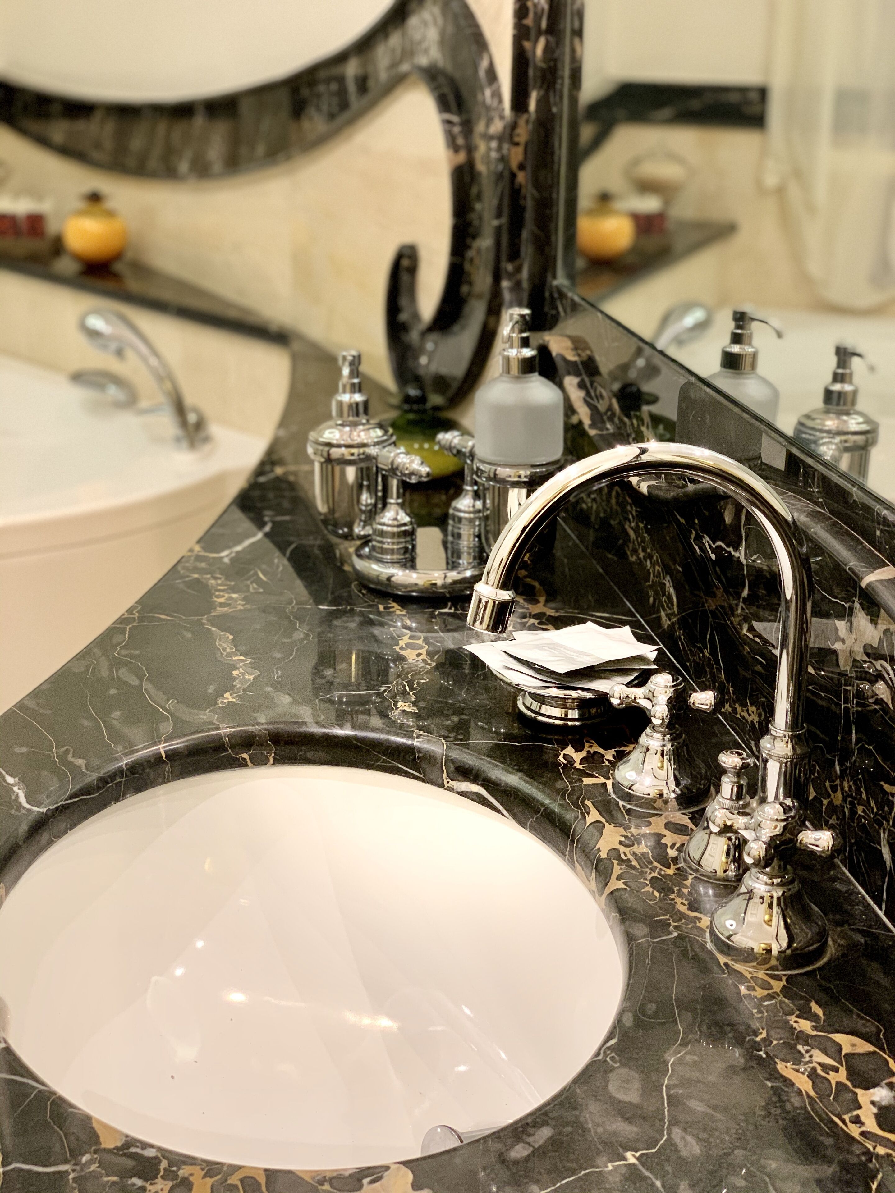 A bathroom with a marble sink, a large mirror, and a modern faucet.