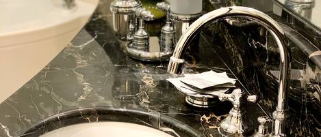 A bathroom with a marble sink, a large mirror, and a modern faucet.