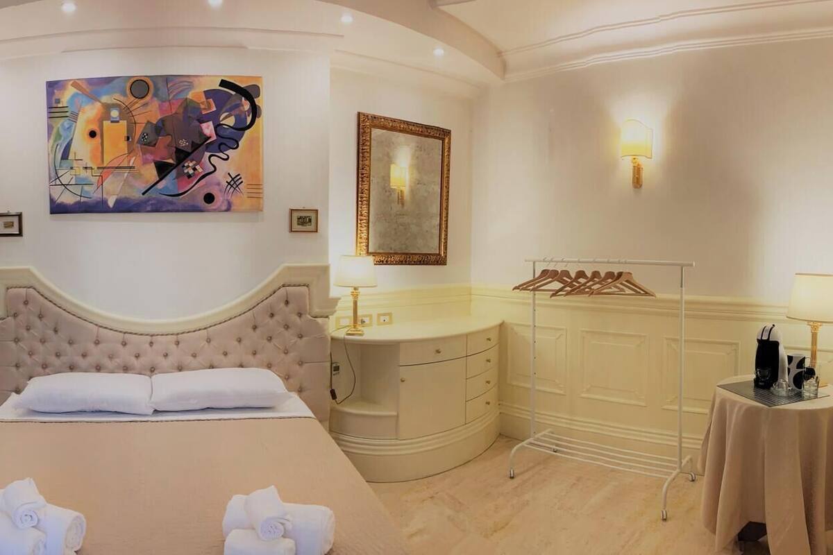 A luxurious bedroom with a large bed, a vanity with a mirror, and a painting on the wall.