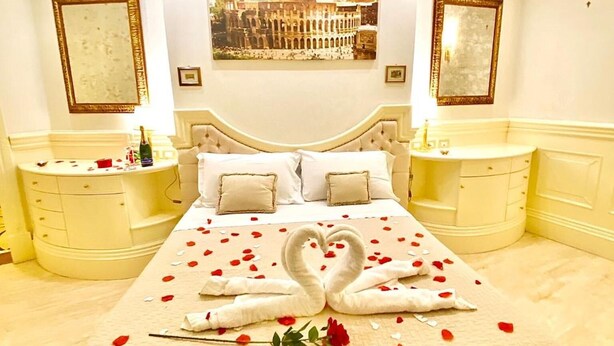 A spacious bedroom with a large bed, two nightstands, and a picture of the Colosseum on the wall. - Simon's Guest House Rome (Rome)
