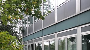 Un edificio moderno con ventanas amplias y barandilla de metal verde.