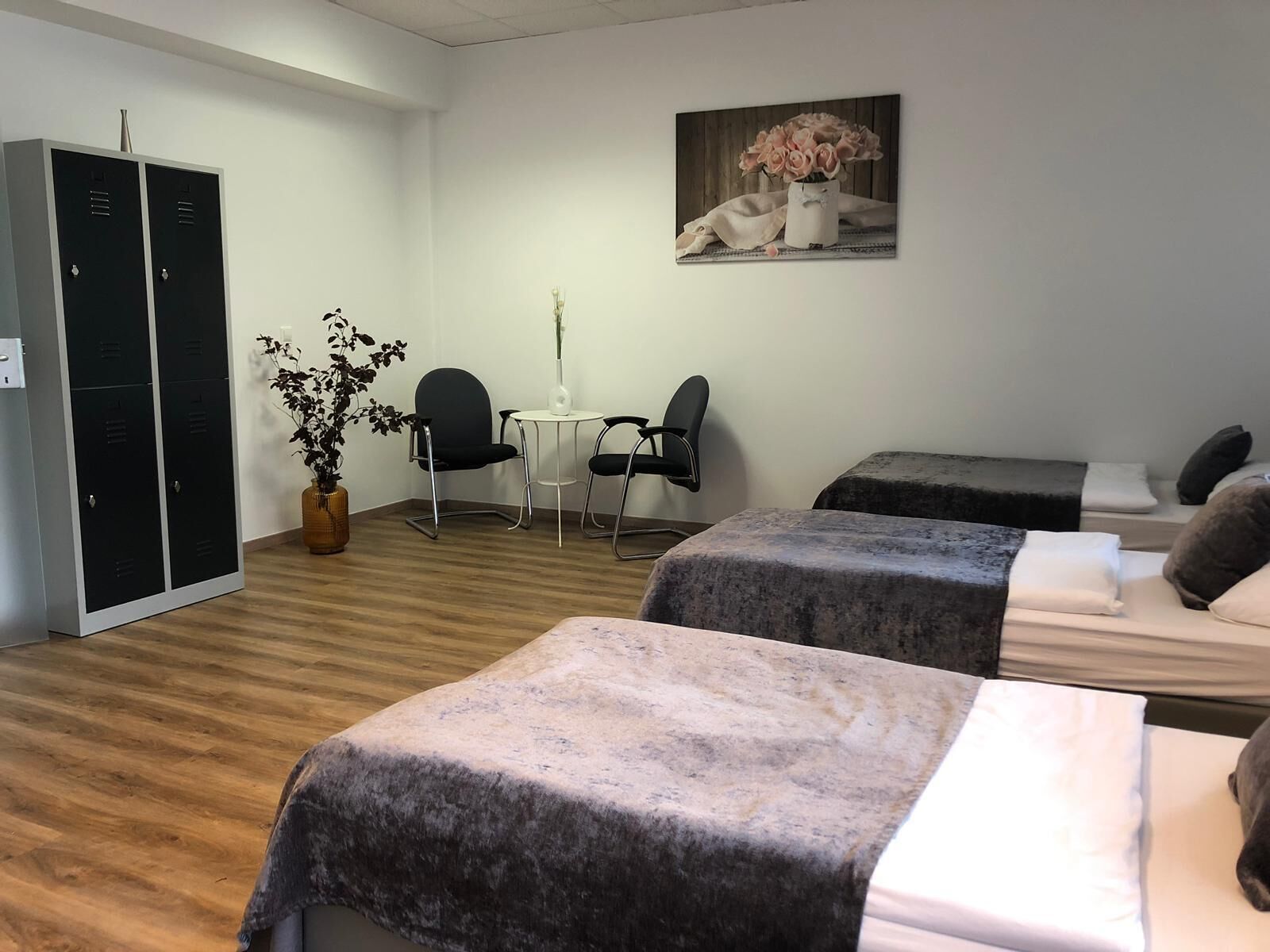 Een hotelkamer met twee bedden, een bureau, stoelen, een potplant en een kledingkast.