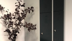 Un armario con dos puertas, un jarrón con flores secas y una cama con una colcha estampada.