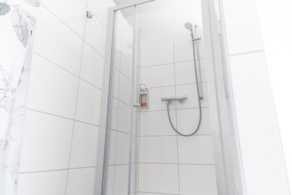Eine Duschkabine mit Handbrause und Armatur an der Wand.