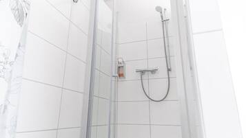 Eine Duschkabine mit Handbrause und Armatur an der Wand.