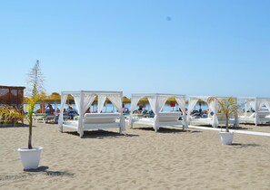 Una playa con camas con dosel blanco dispuestas en filas.