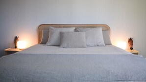 Ein Bett mit einem gewobenen Kopfteil, zwei Nachttischlampen und einem neutralen Farbdesign.