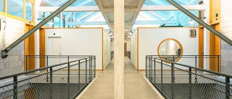 A corridor with a high ceiling, concrete pillars, and a glass roof.
