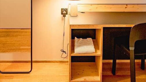 A room with a wooden desk, a chair, a whiteboard, and a lamp.