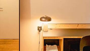 A room with a wooden desk, a chair, a whiteboard, and a lamp.