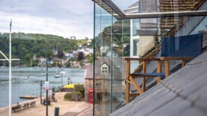 Ein modernes Gebäude mit einem Glasbalkon mit Blick auf einen Hafen.