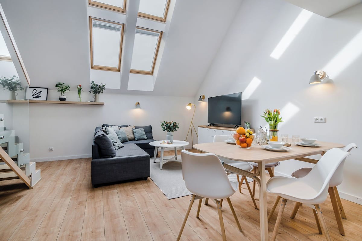 Ein modernes Loft-Apartment mit Essbereich, einer Couch und einem Fernseher.