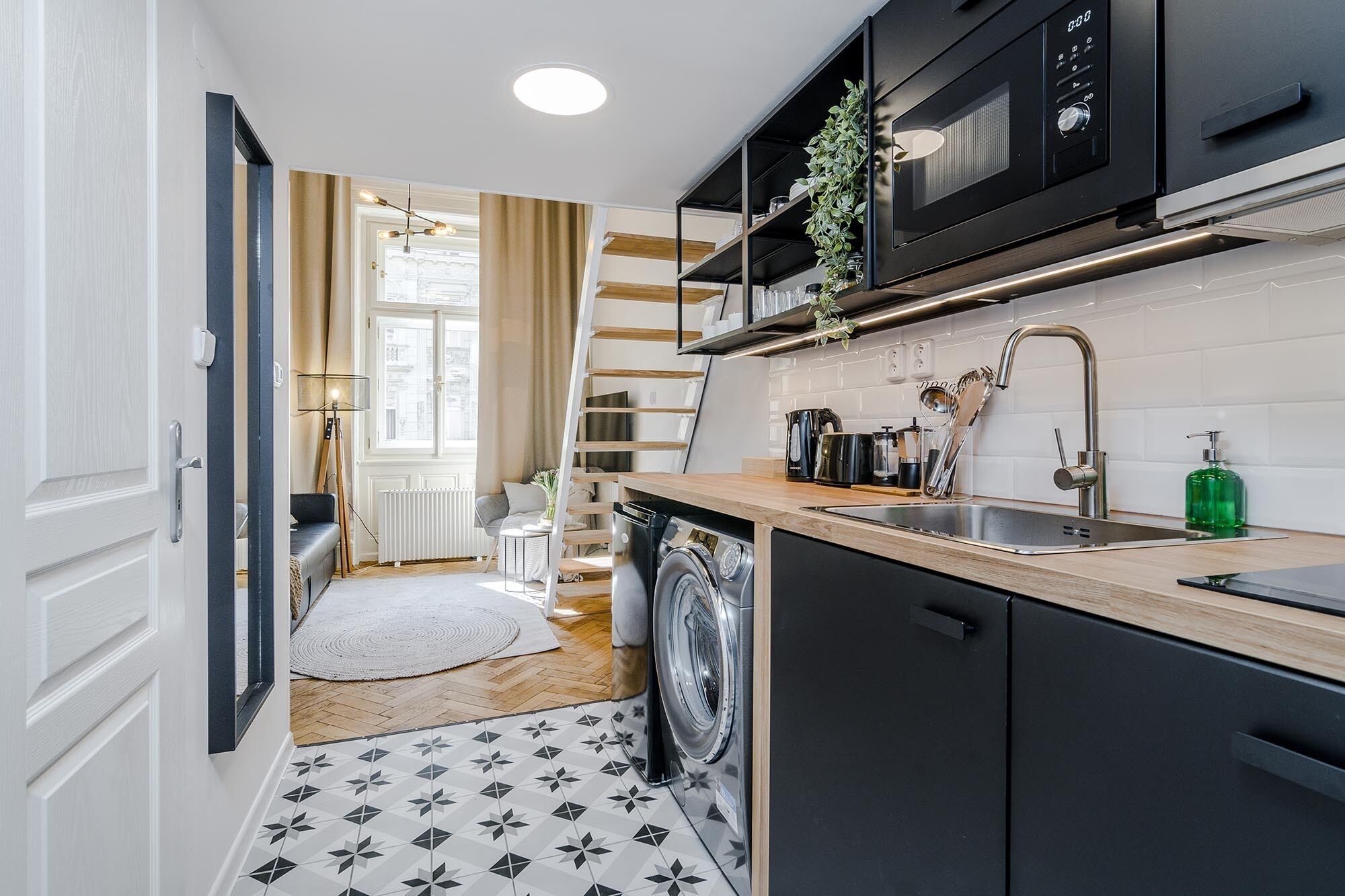 Une cuisine compacte équipée d’un lave-linge, d’un four à micro-ondes et d’un évier.