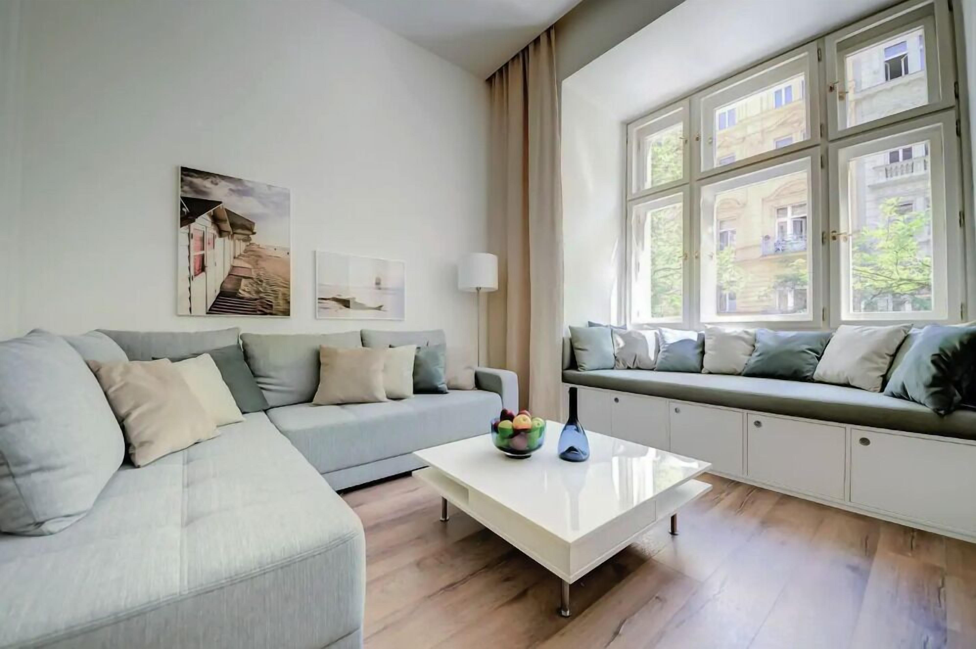 Una sala de estar moderna con un sofá, una mesa de centro y una ventana con vistas a edificios.