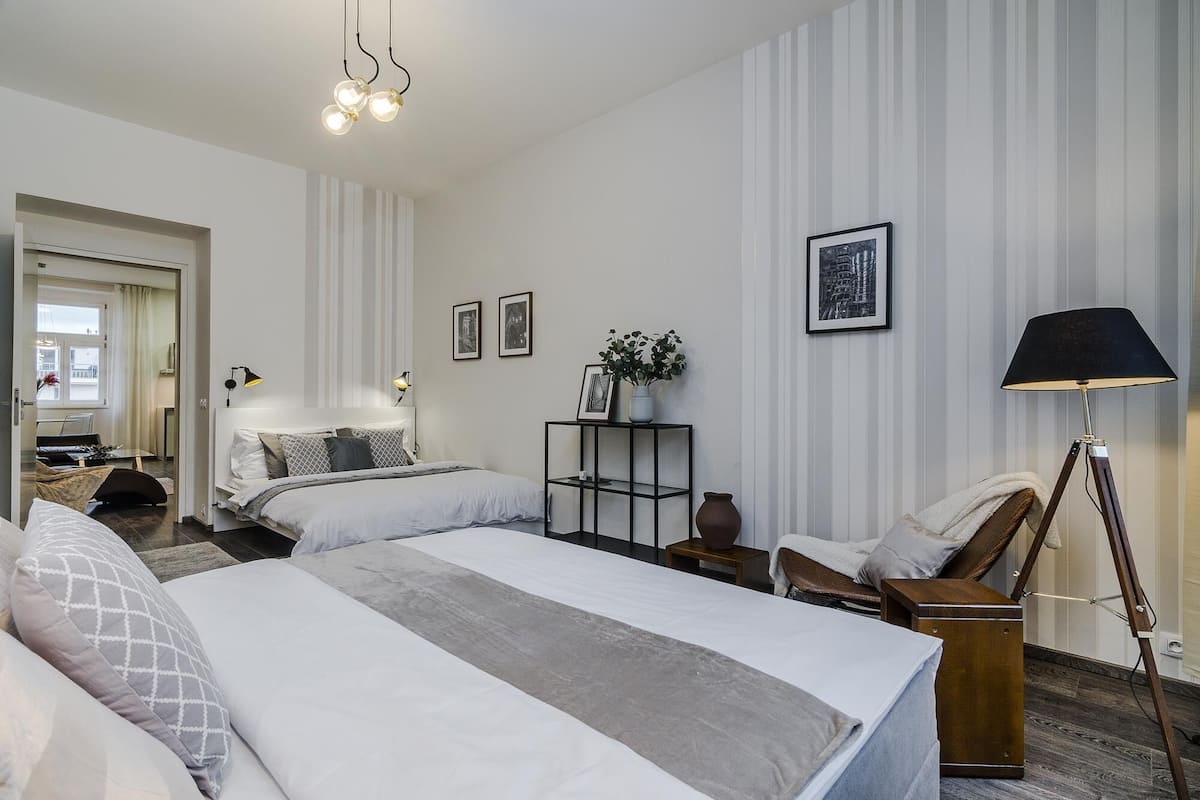 Ein modernes Hotelzimmer mit zwei Betten, einem Schreibtisch, einem Stuhl, einer Lampe und einem Bücherregal.
