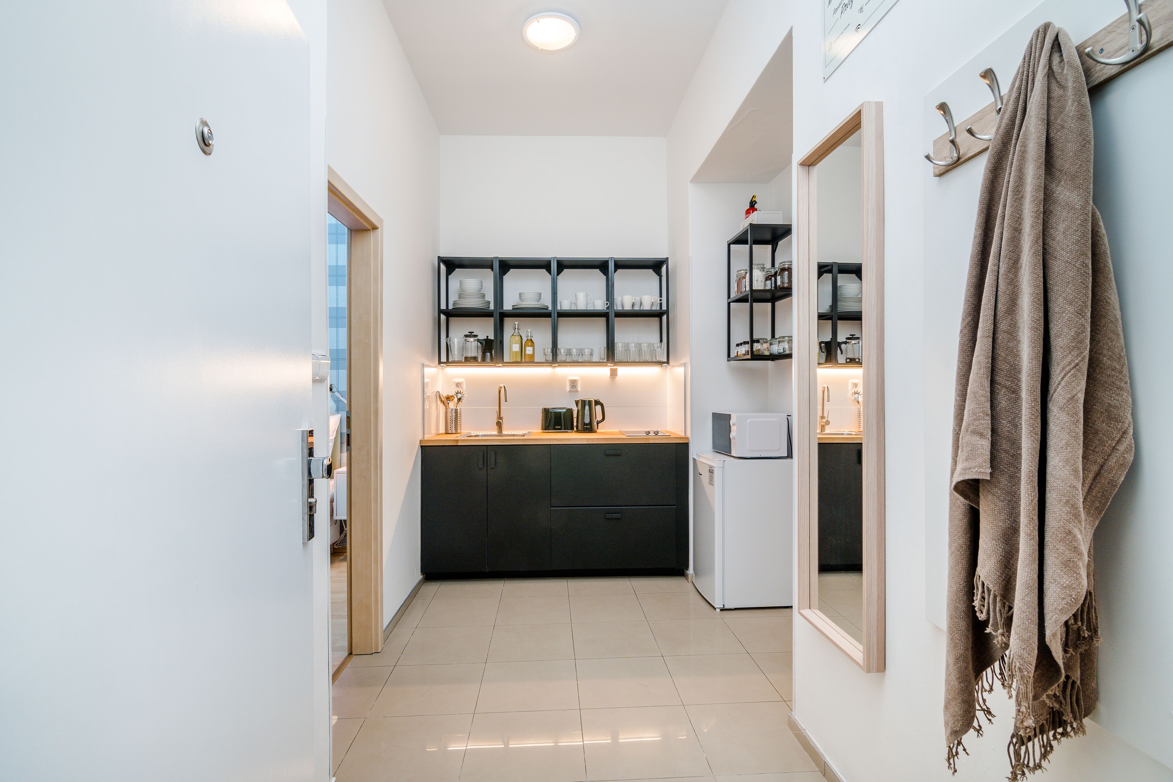 Una cocina estrecha con armarios negros, un refrigerador blanco y una encimera de madera.
