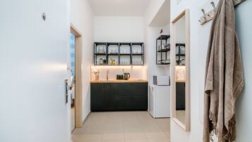 Una cocina estrecha con armarios negros, un refrigerador blanco y una encimera de madera.