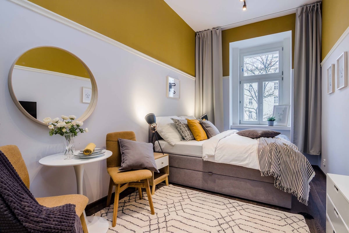 Ein Schlafzimmer mit Bett, Nachttisch, Stuhl und einem Fenster mit Vorhängen.