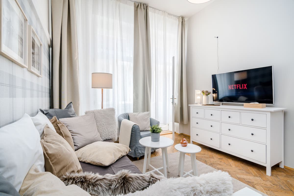 Ein modernes Wohnzimmer mit einer Couch, einem Fernseher, einem weißen Schrank und einem Tisch mit einer Pflanze.