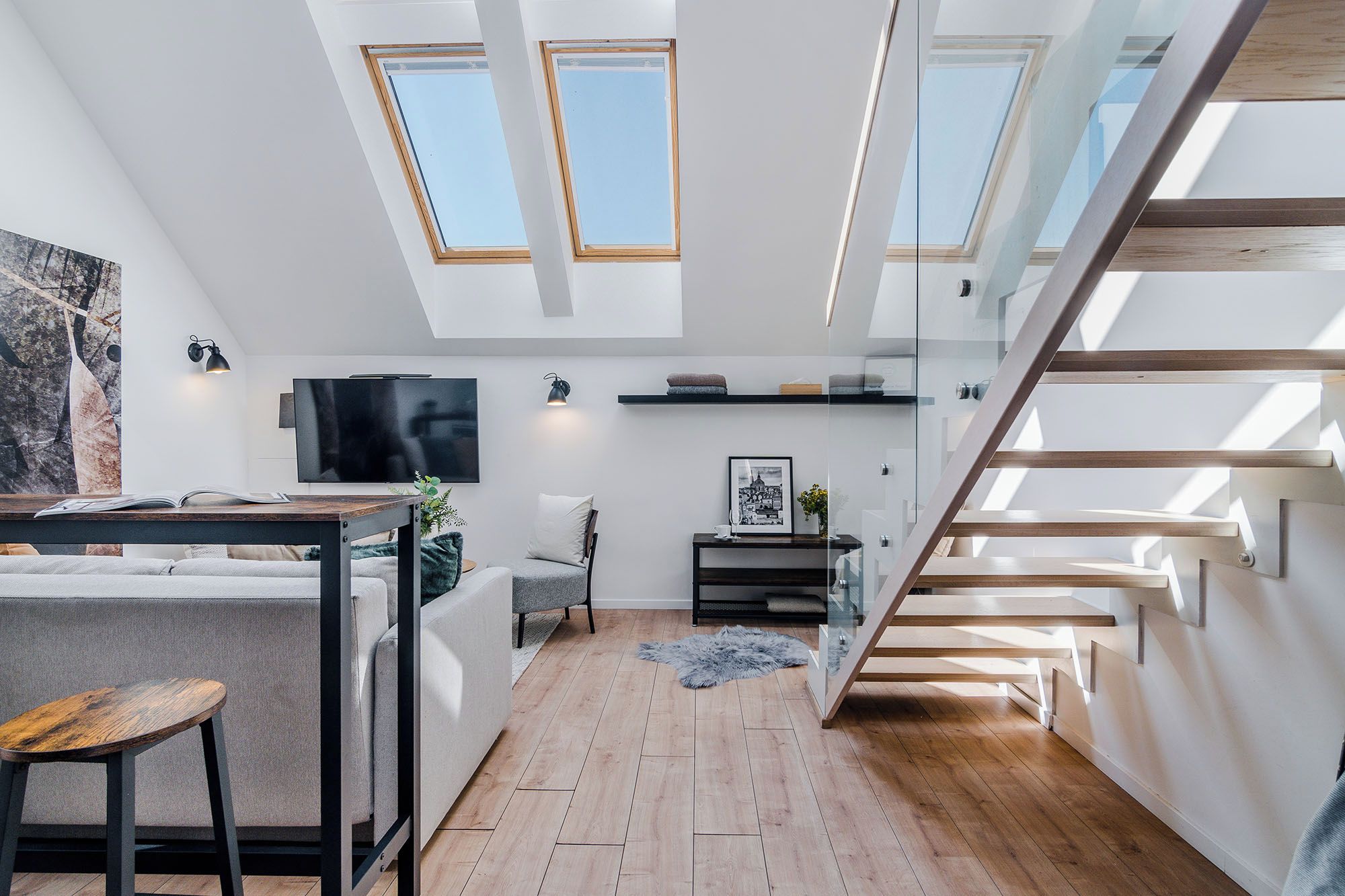 Un interno moderno con design in stile loft, caratterizzato da una scala, una TV a schermo piatto e un’accogliente zona salotto.