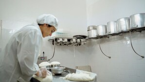 A chef in a white uniform working in a kitchen with stainless steel pots and a food preparation area. - Vumba - Beira Suite (Arganil)
