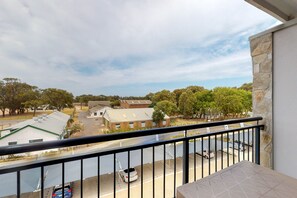 A balcony with a view of a street, buildings, and trees.