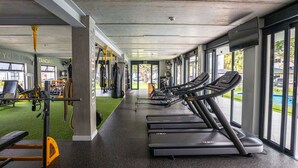 A gym with treadmills, weight machines, and a green exercise area. - The Jade Estate Somerset West (Cape Town)