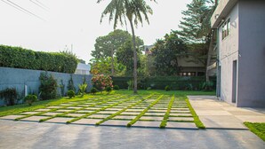 A courtyard with a patterned lawn, a concrete pathway, and a building on one side.