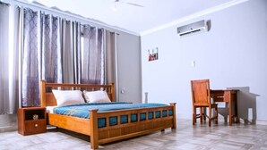 A bedroom with a wooden bed, a nightstand, a desk, and a chair.