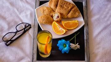Una bandeja con croissants, rodajas de naranja y una bebida con una rodaja de limón.