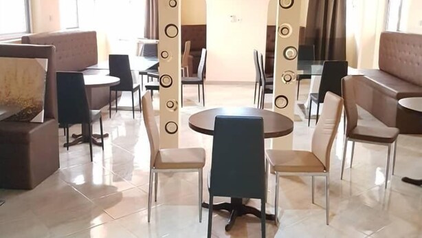 A spacious lobby with a high ceiling, a central sun-shaped decoration, and a mix of seating areas including sofas and chairs.