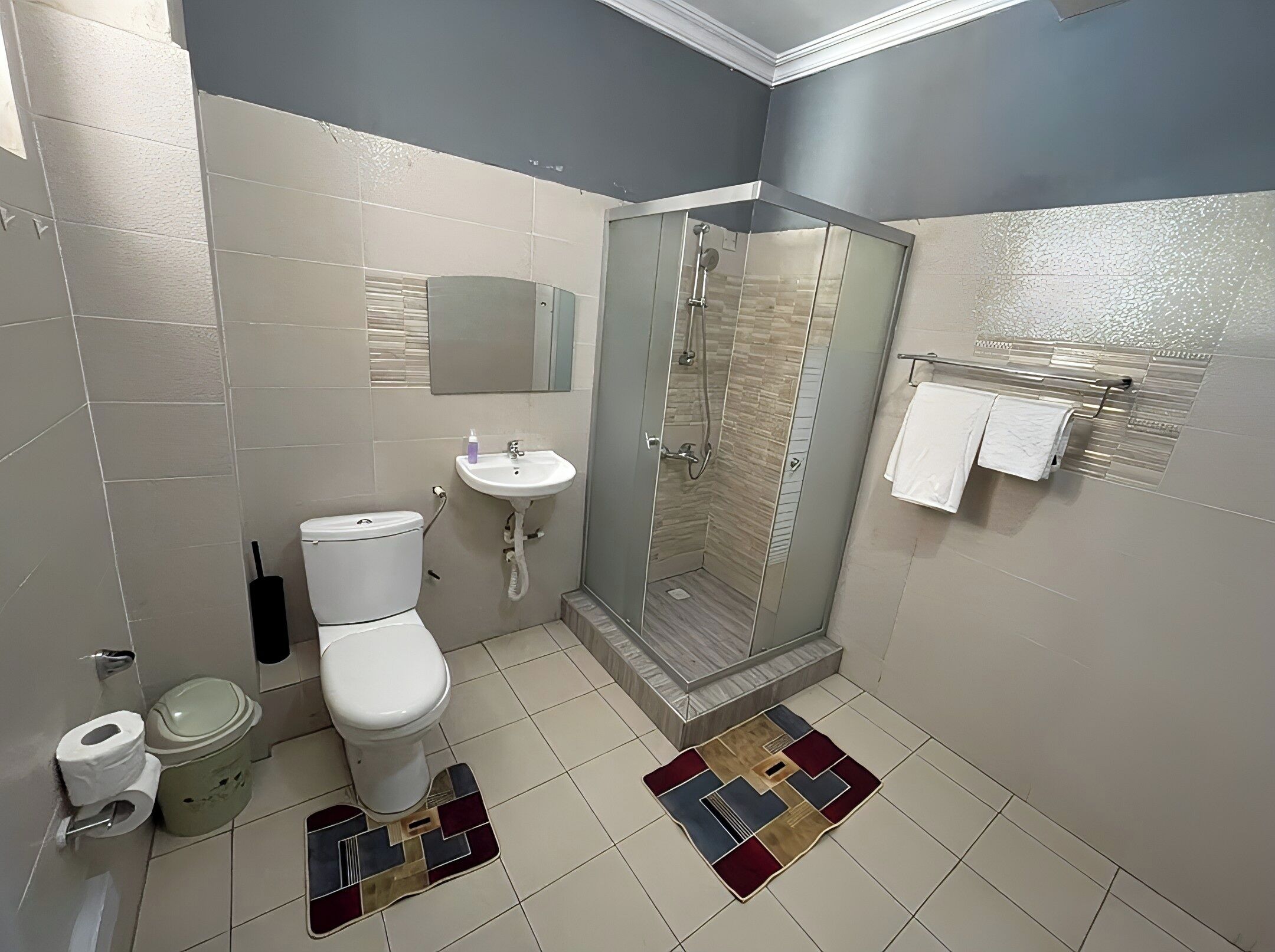 Un baño con inodoro, lavamanos y cabina de ducha de vidrio.