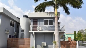 A two-story residential building with a balcony, air conditioning units, and a wooden fence.