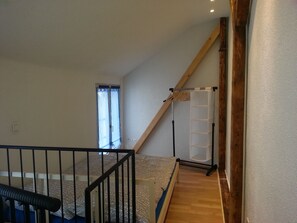 A bedroom with a wooden staircase, a window with curtains, and a bed with patterned bedding. - heidelbed-Ferienwohnung Heidelberg (Heidelberg)