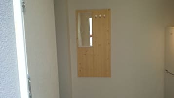 A room with a wooden door, a small mirror, and a light switch on the wall.