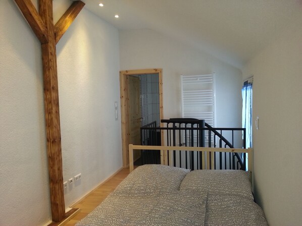 A room with a wooden beam structure, a staircase, and a bed with patterned bedding. - heidelbed-Ferienwohnung Heidelberg (Heidelberg)