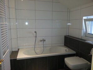 A modern bathroom with a bathtub, a toilet, and a window. - heidelbed-Ferienwohnung Heidelberg (Heidelberg)
